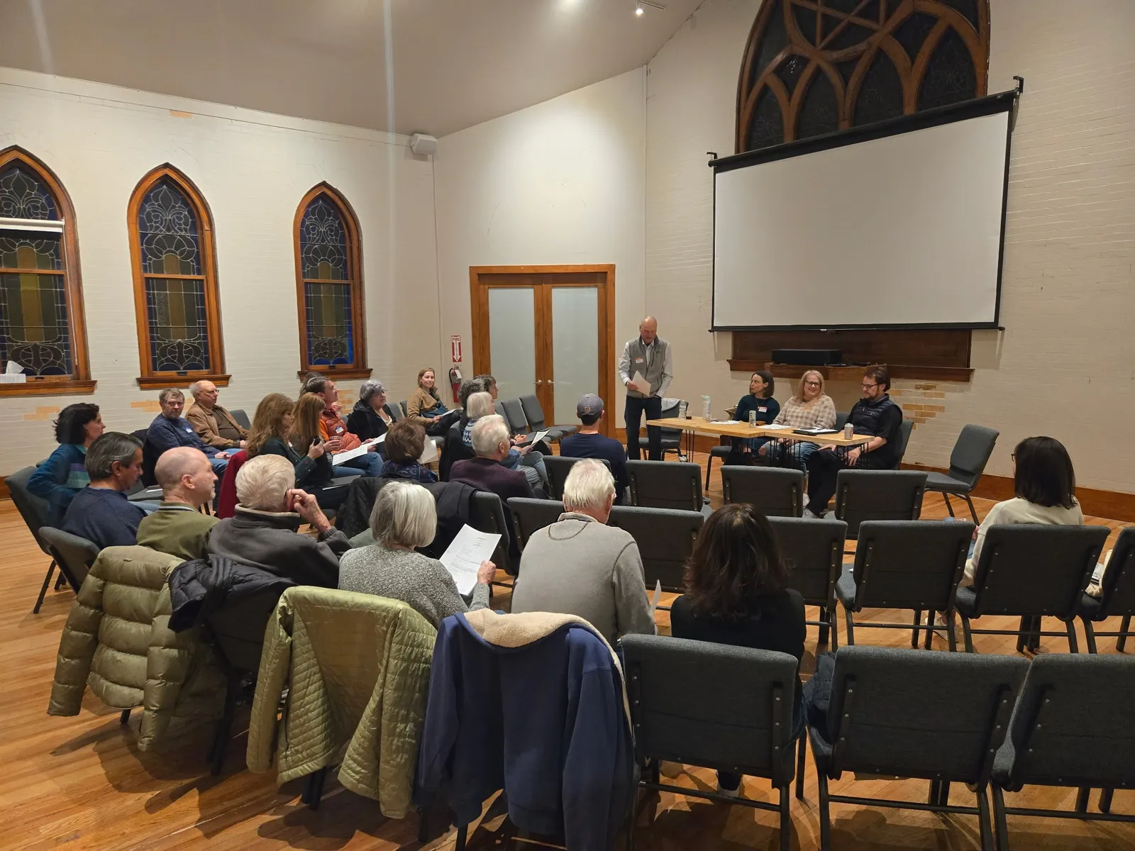 A community congregation gathers in a circle of chairs for a discussion in the main hall