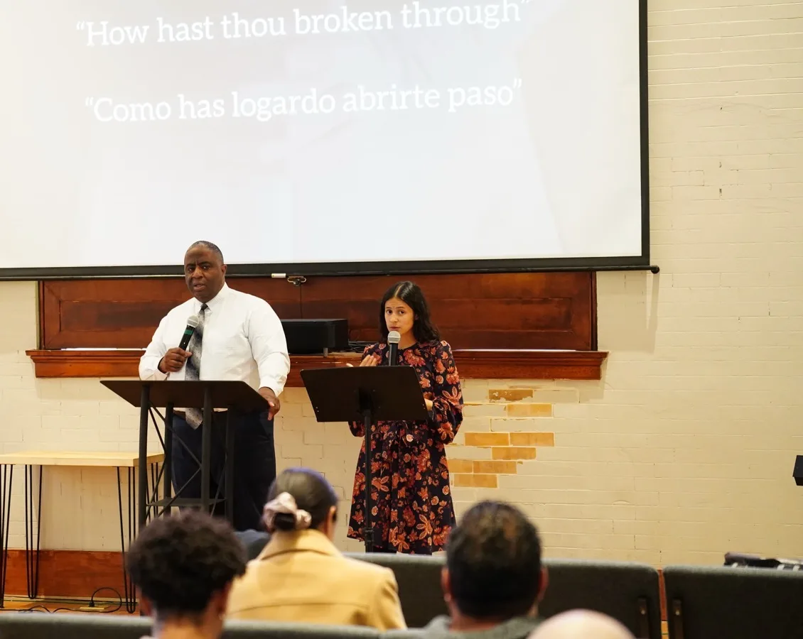 Pastor Tate preaches beside an interpreter during a bilingual Sunday service in the hall