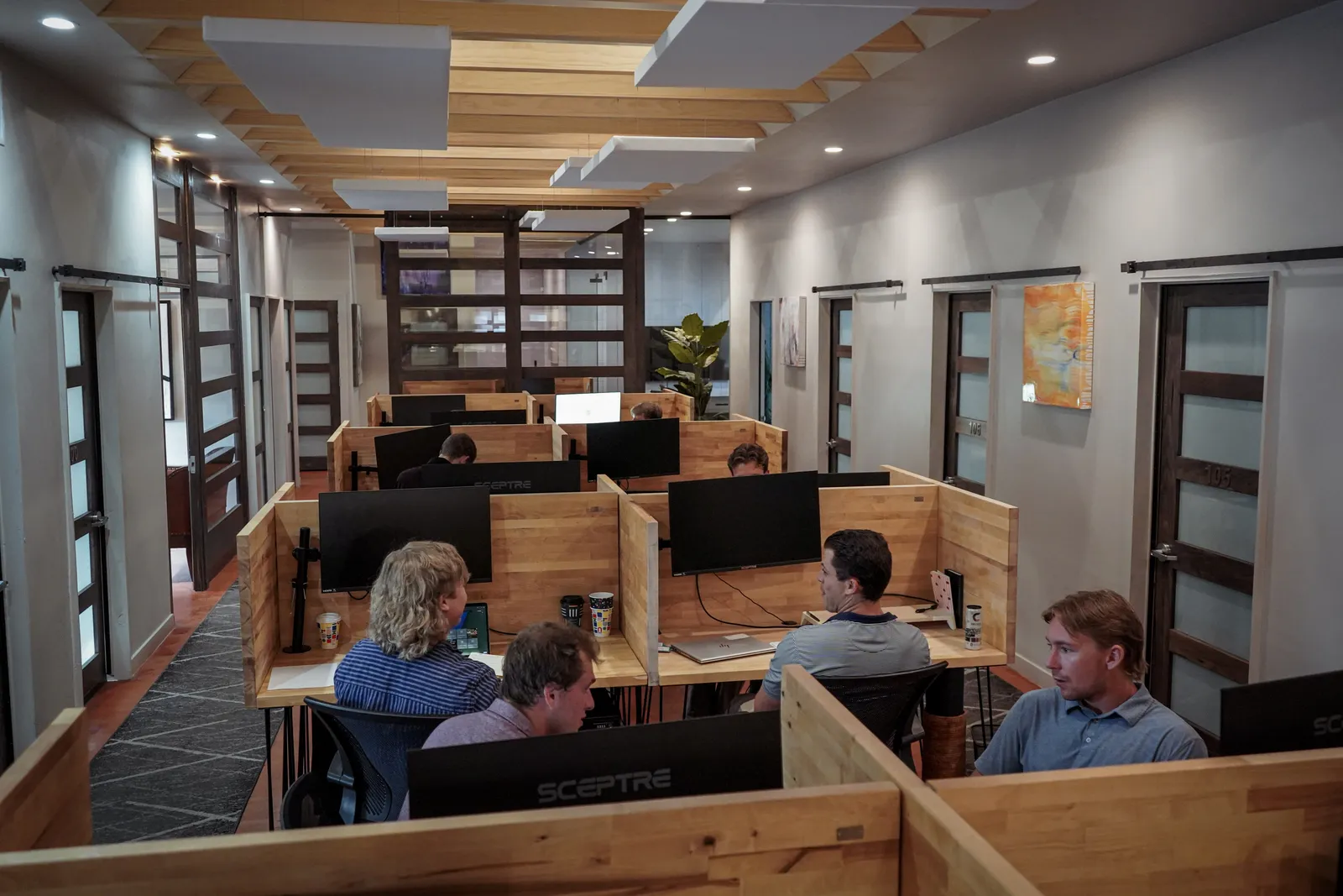 Members work at dedicated desks in the wood-beamed coworking hall at Merritt Workspace