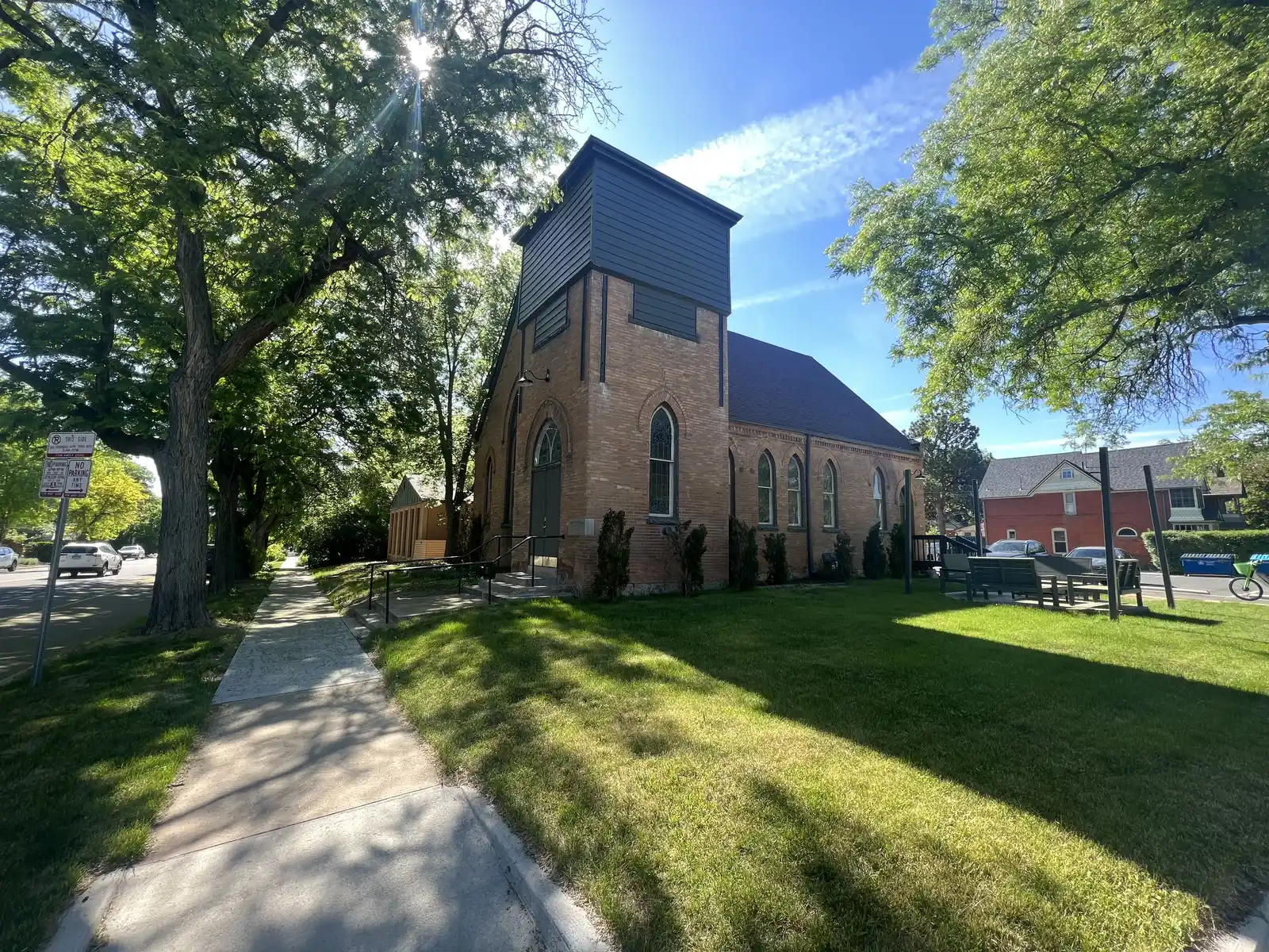 The historic brick building seen from the tree-lined sidewalk on a sunny summer day