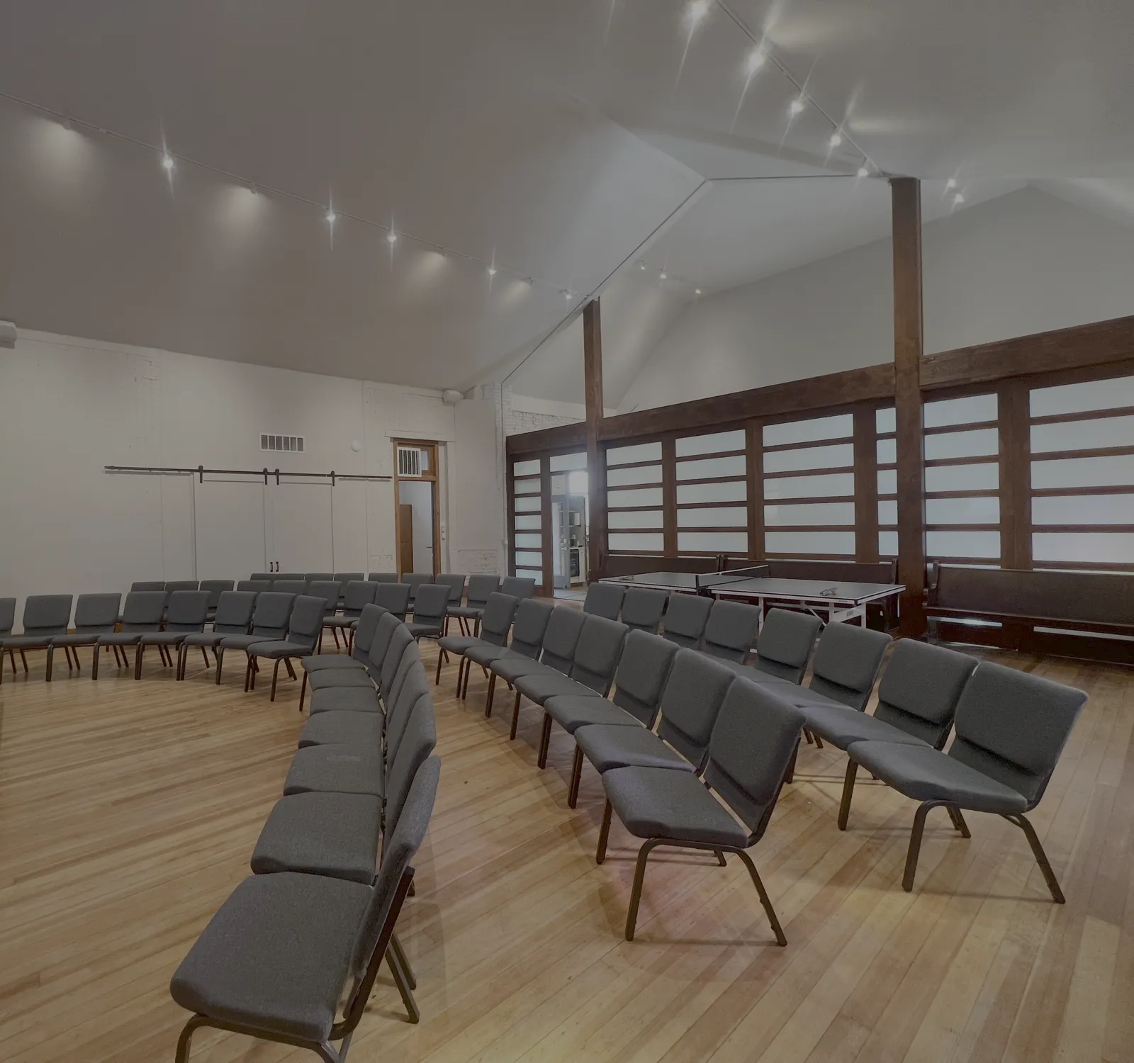 Rows of chairs arranged in a semicircle across the wood floor of the vaulted event hall