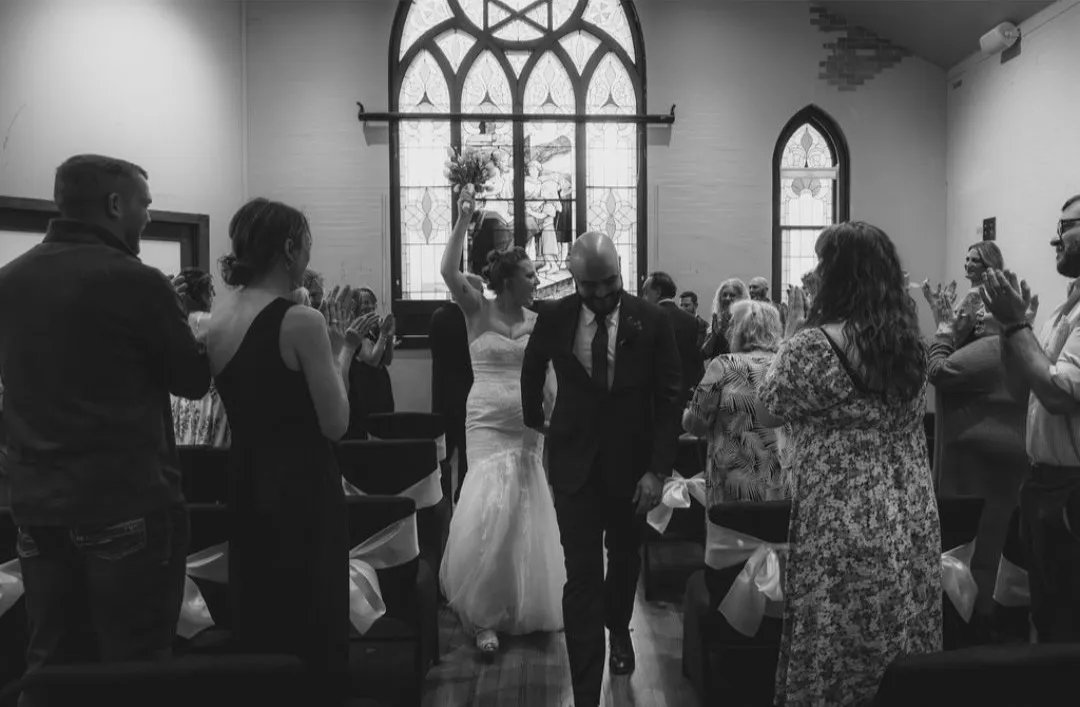 Newlyweds walk back down the aisle to applause beneath the sanctuary's stained-glass windows