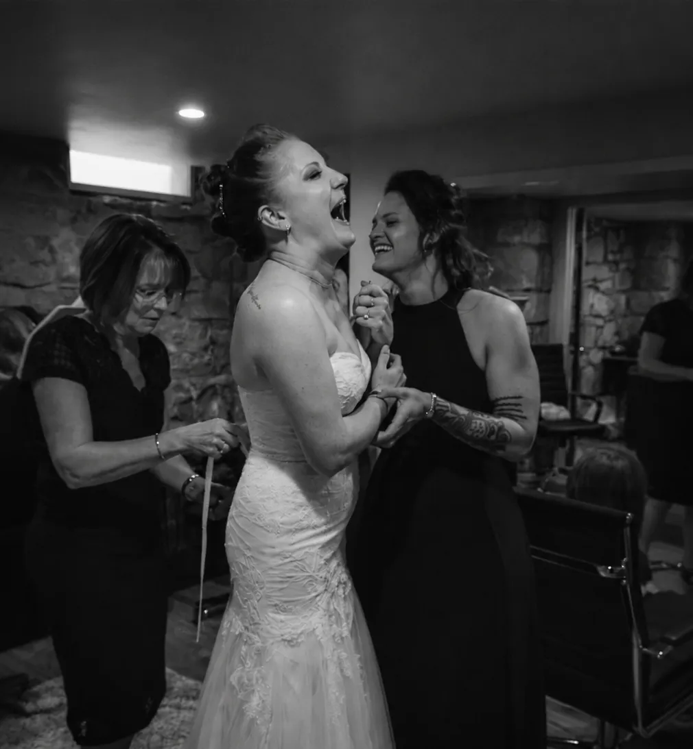 A bride laughs with her attendants while getting ready in the venue's stone-walled suite